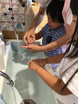 保育士と一緒に指の先まで手洗いする子ども